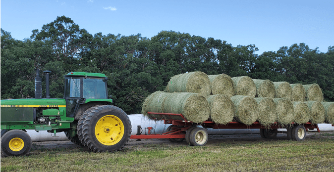 A tractor pulling a trailer filled with hay.