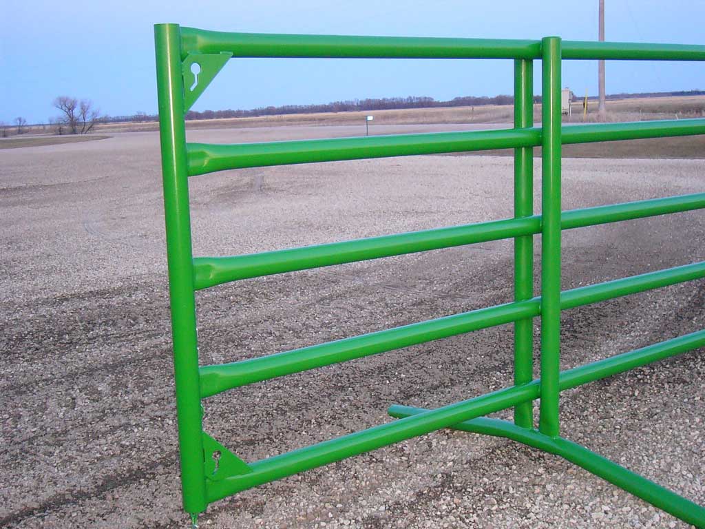 A green metal fence in the middle of a field.